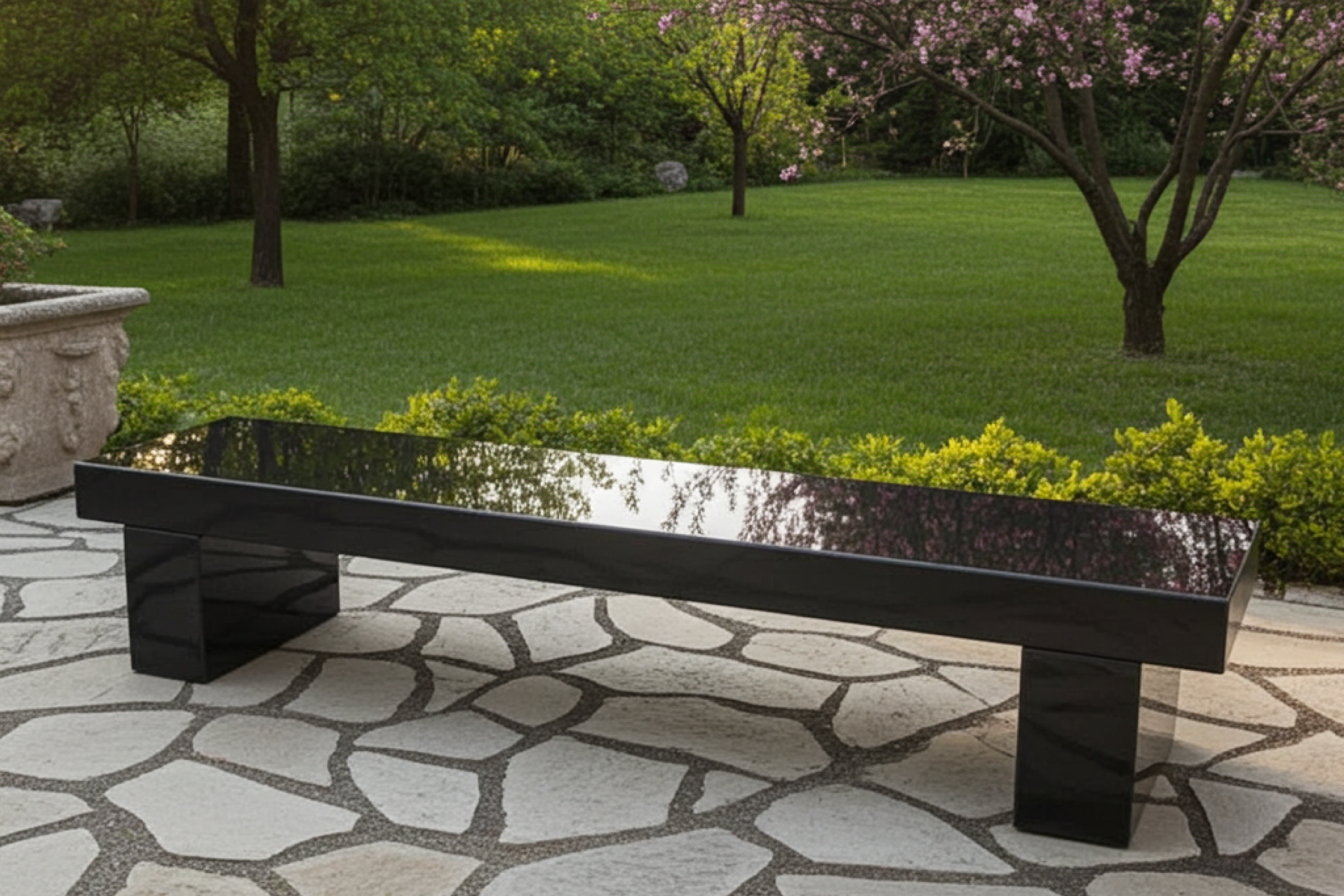 Black marble bench on a stone patio with green grass and trees in Abu Dhabi