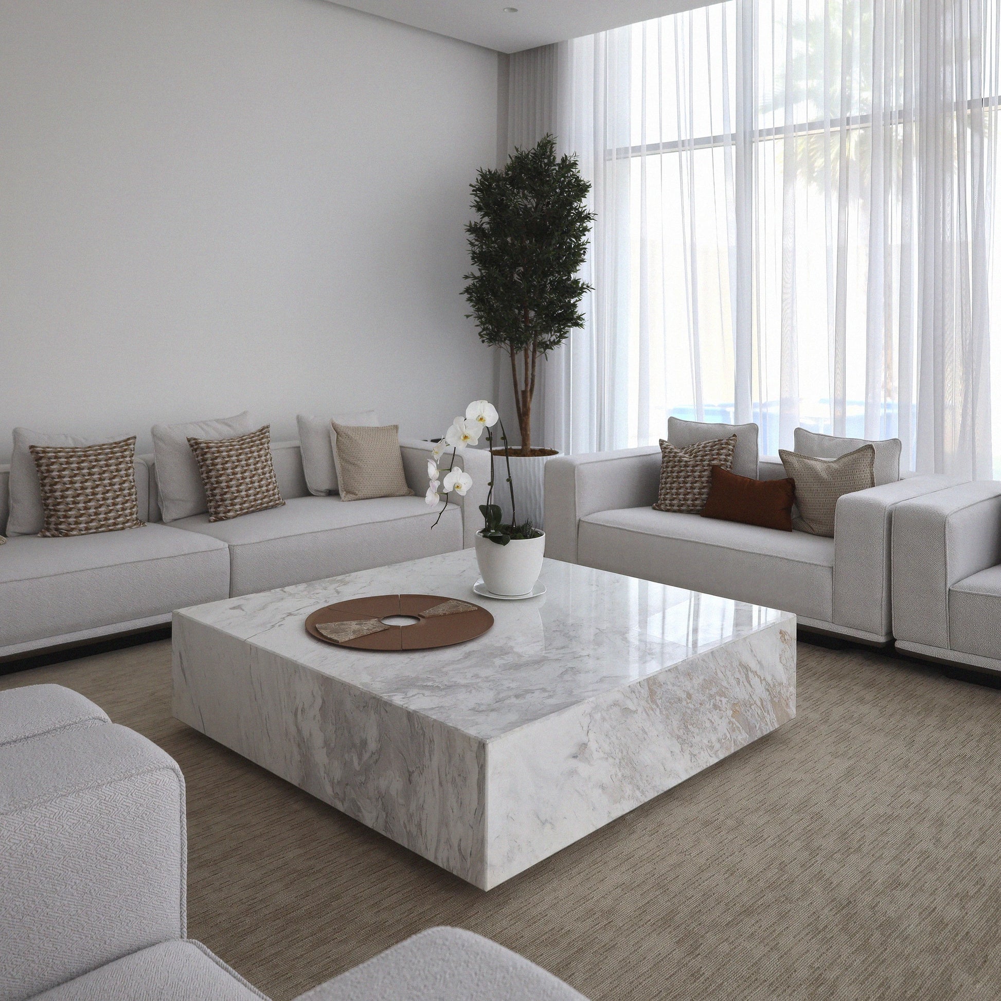 Bamo square marble coffe table from Marbeya Charm in the midldle of modern living room, surrounded with light grey sofas, a large window with normal lighting and transparent curtains, an artificial tree in the corner