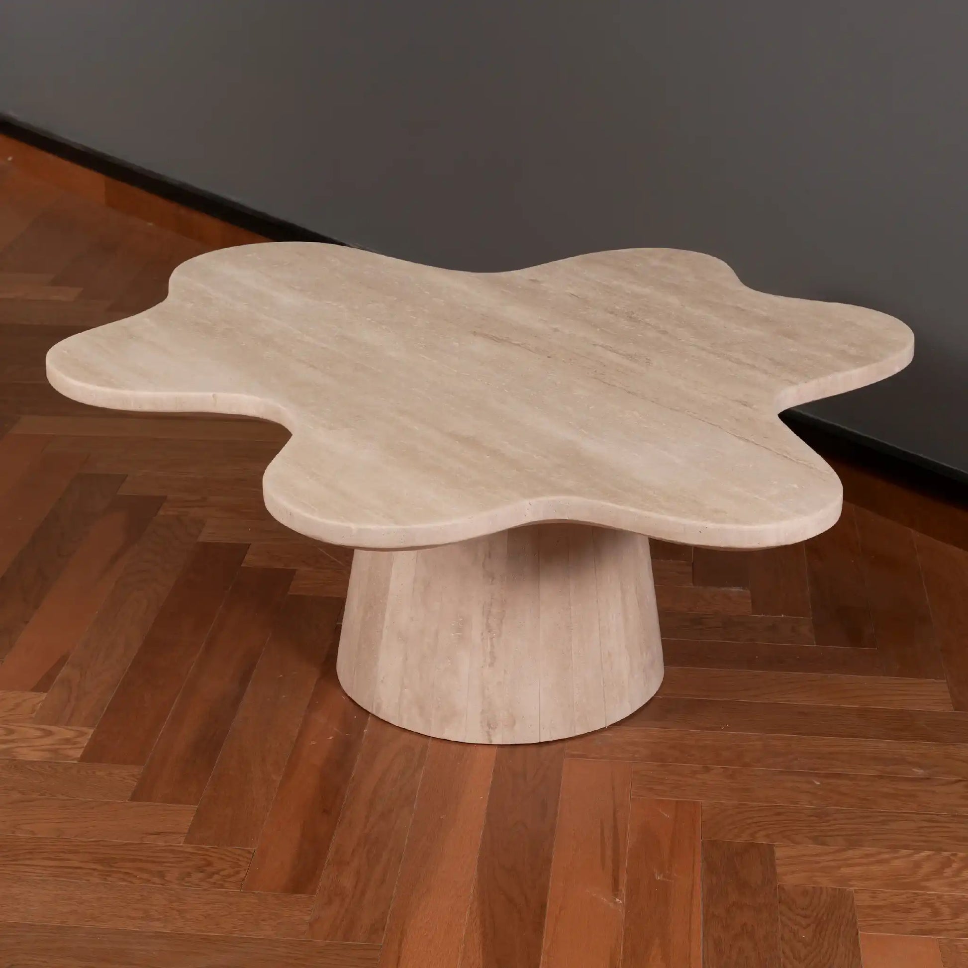Petalo Travertine Coffee table with a unique, flower-like design on a wooden floor and dark wall in background.