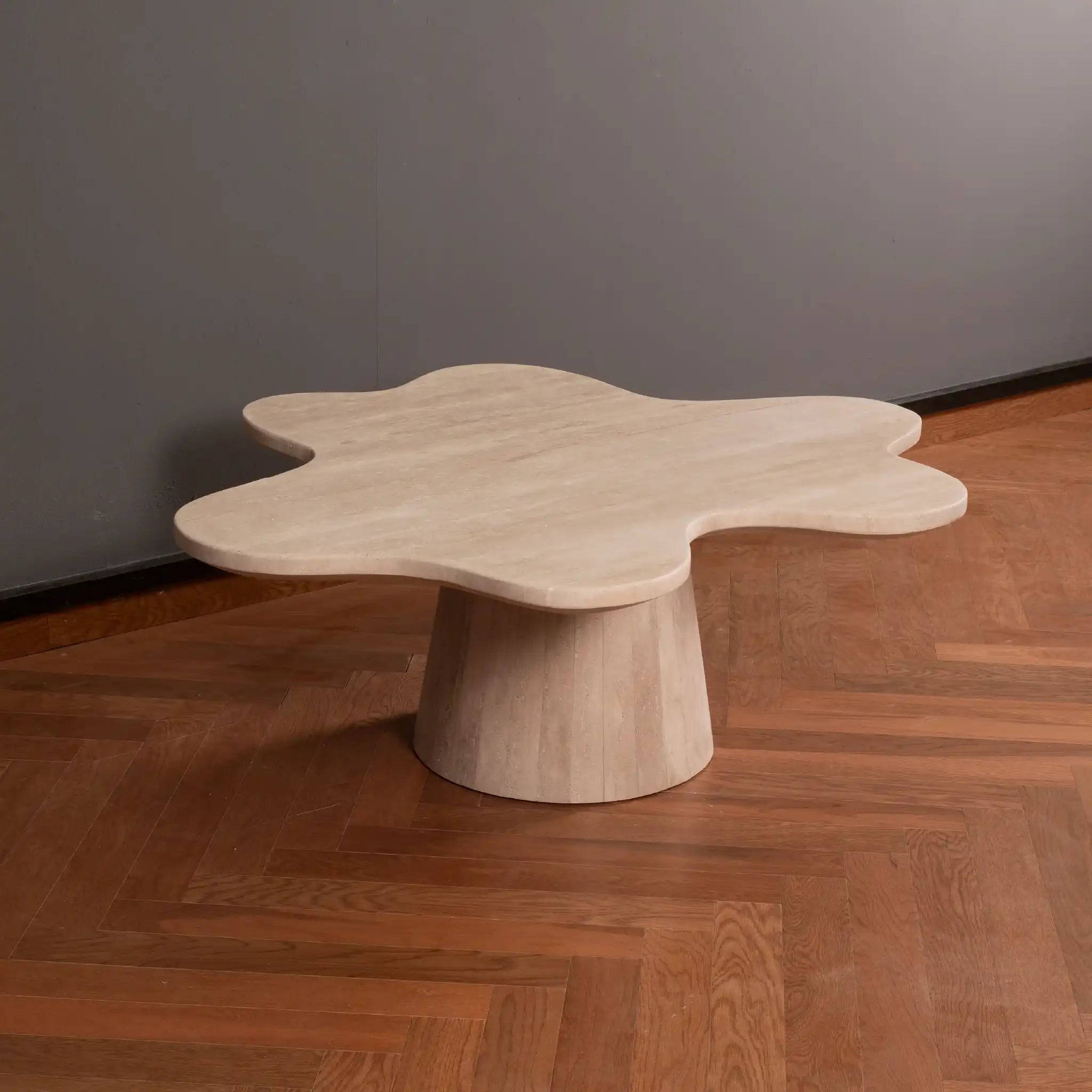 Petalo Travertine Coffee table with a unique design on a wooden floor against a gray wall