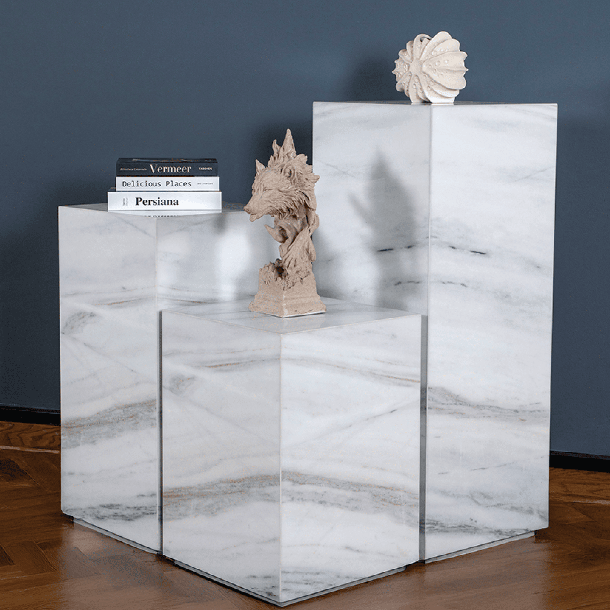 Marble plinth with decorative items against a dark wall.